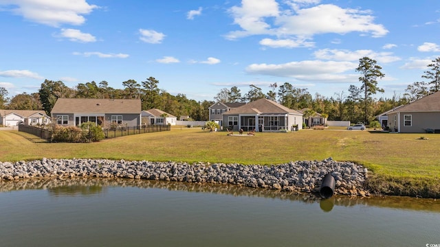 back of property with a lawn, a sunroom, and a water view