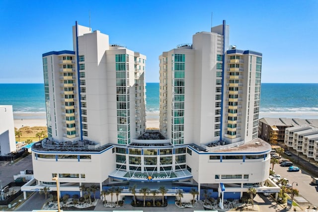 view of building exterior with a beach view and a water view