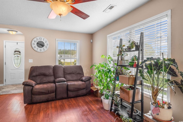 living room featuring ceiling fan, dark wood-type flooring, and a textured ceiling