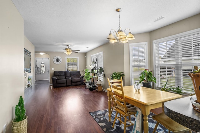 dining room with ceiling fan with notable chandelier, dark hardwood / wood-style flooring, and a textured ceiling