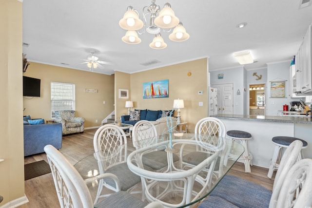 dining room featuring ceiling fan with notable chandelier, light hardwood / wood-style floors, and ornamental molding