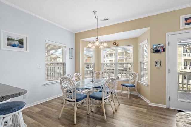 dining area with a notable chandelier, wood-type flooring, and crown molding