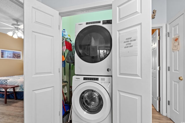 washroom with a textured ceiling, light hardwood / wood-style floors, ceiling fan, and stacked washer and clothes dryer