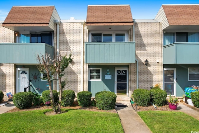 view of front facade featuring a front yard and a balcony