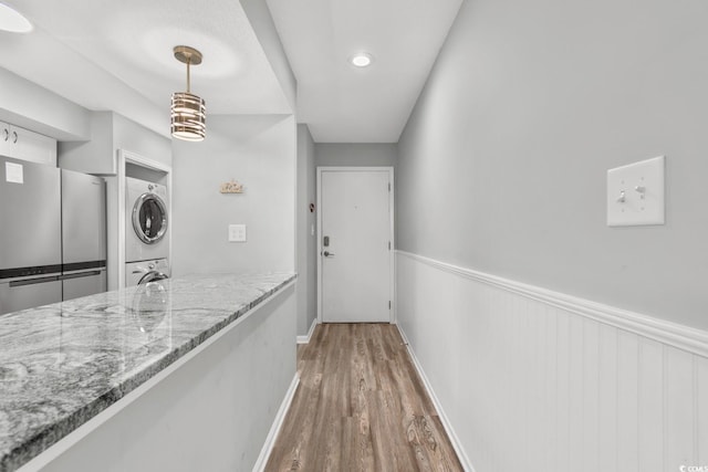 hallway featuring dark hardwood / wood-style flooring and stacked washer and dryer