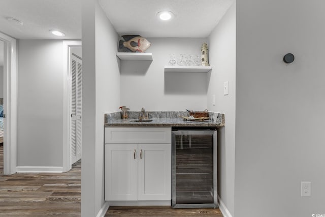 bar featuring sink, wine cooler, dark hardwood / wood-style flooring, a textured ceiling, and white cabinets