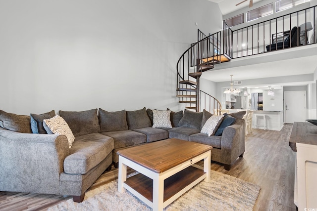 living room featuring light hardwood / wood-style flooring, a high ceiling, and a notable chandelier