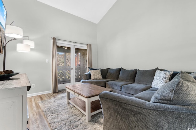 living room with light wood-type flooring and high vaulted ceiling