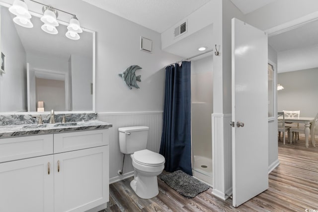 bathroom with walk in shower, vanity, a textured ceiling, hardwood / wood-style floors, and toilet