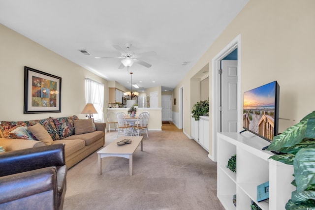 living room featuring light carpet and ceiling fan with notable chandelier