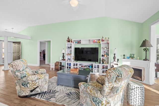 living room with wood finished floors, decorative columns, a ceiling fan, and vaulted ceiling