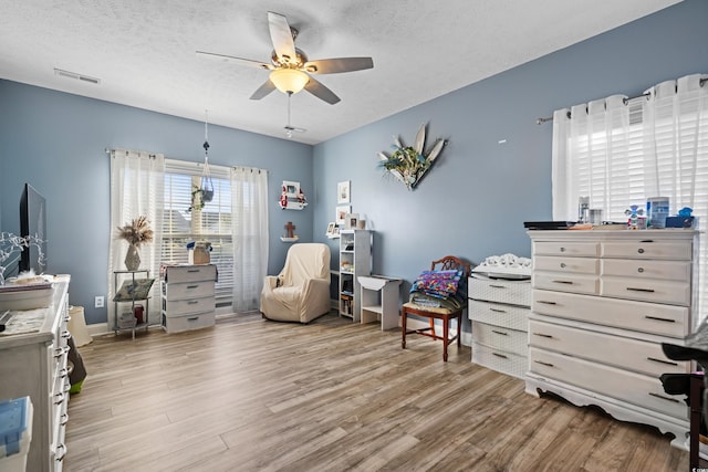 bedroom with light wood-style floors, visible vents, and a textured ceiling