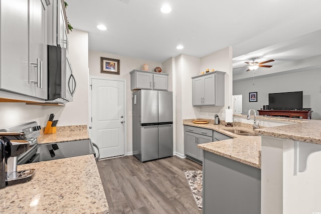 kitchen featuring appliances with stainless steel finishes, light wood-type flooring, gray cabinetry, and sink