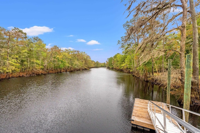 view of dock with a water view and a wooded view
