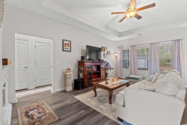 living area featuring baseboards, a tray ceiling, a ceiling fan, and wood finished floors