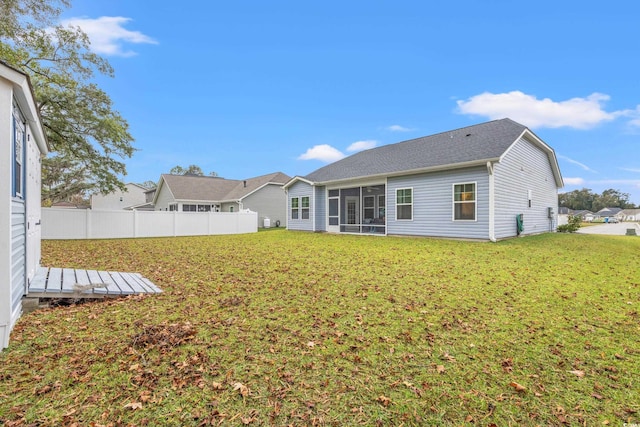 rear view of house with a yard and a sunroom