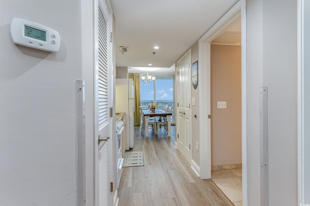 hall with a chandelier and light hardwood / wood-style flooring