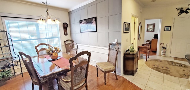 dining area featuring crown molding, an inviting chandelier, and light wood-type flooring