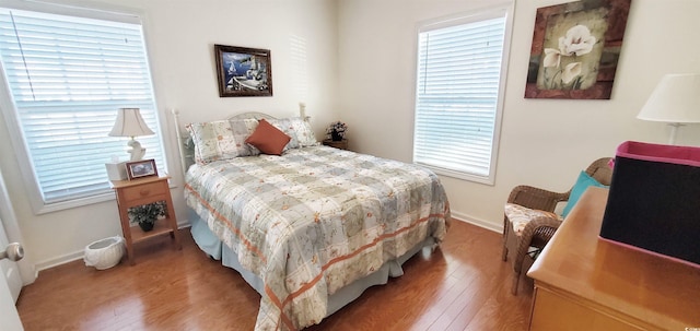 bedroom featuring baseboards, multiple windows, and wood finished floors