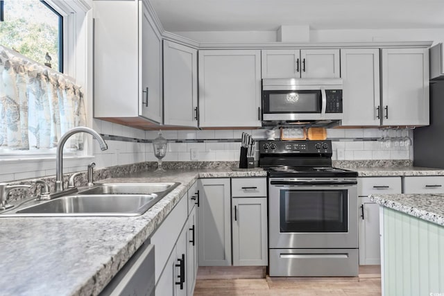 kitchen with light hardwood / wood-style flooring, sink, stainless steel appliances, and tasteful backsplash