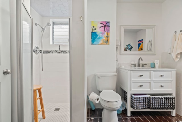 bathroom with a tile shower, tile patterned flooring, vanity, and toilet