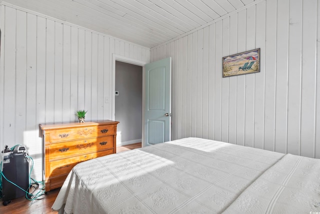 bedroom with wood-type flooring and wooden walls