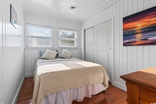 bedroom featuring dark hardwood / wood-style floors, wood ceiling, a closet, and wood walls