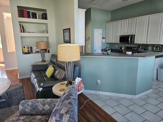 kitchen featuring white cabinets, kitchen peninsula, stainless steel appliances, and light hardwood / wood-style flooring