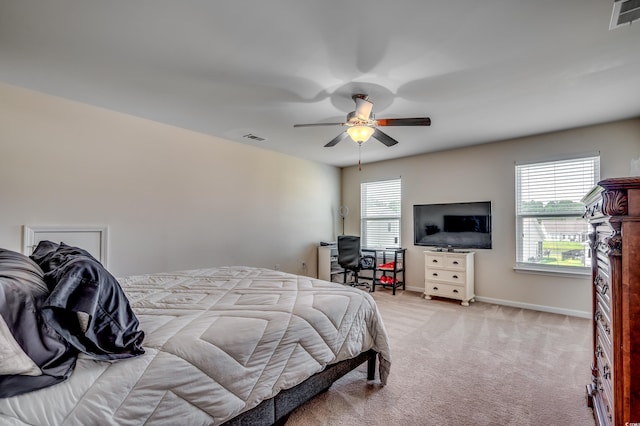 bedroom featuring ceiling fan, light carpet, and multiple windows