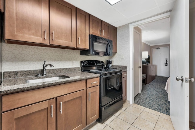 kitchen featuring dark stone counters, black appliances, sink, light tile patterned floors, and ornamental molding