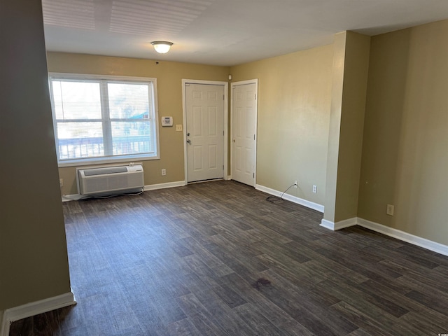 unfurnished room featuring a wall unit AC and dark hardwood / wood-style flooring