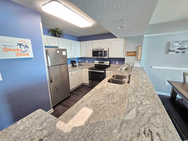 kitchen with light stone countertops, sink, stainless steel appliances, dark hardwood / wood-style flooring, and white cabinets