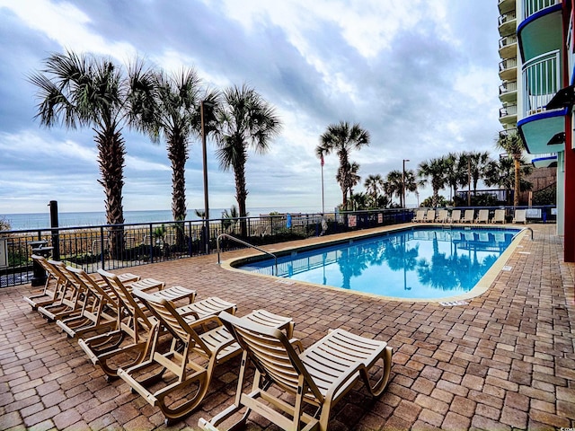 view of swimming pool with a water view and a patio area