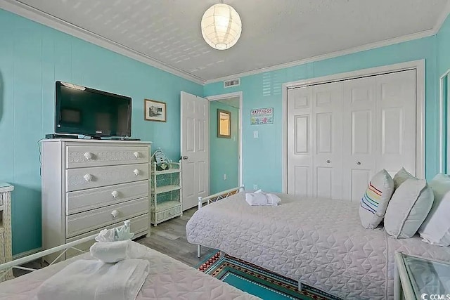 bedroom with light hardwood / wood-style flooring, a closet, and ornamental molding