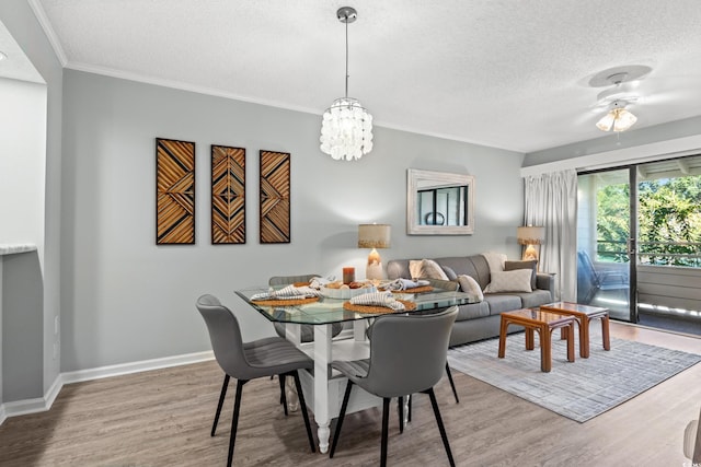 dining area with crown molding, ceiling fan, wood-type flooring, and a textured ceiling