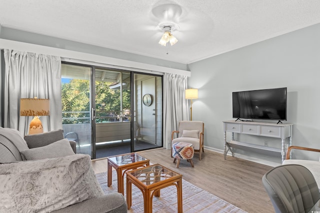 living room featuring hardwood / wood-style floors, ceiling fan, ornamental molding, and a textured ceiling