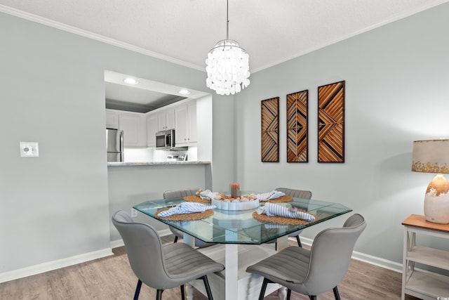 dining space featuring crown molding, light hardwood / wood-style flooring, a textured ceiling, and an inviting chandelier