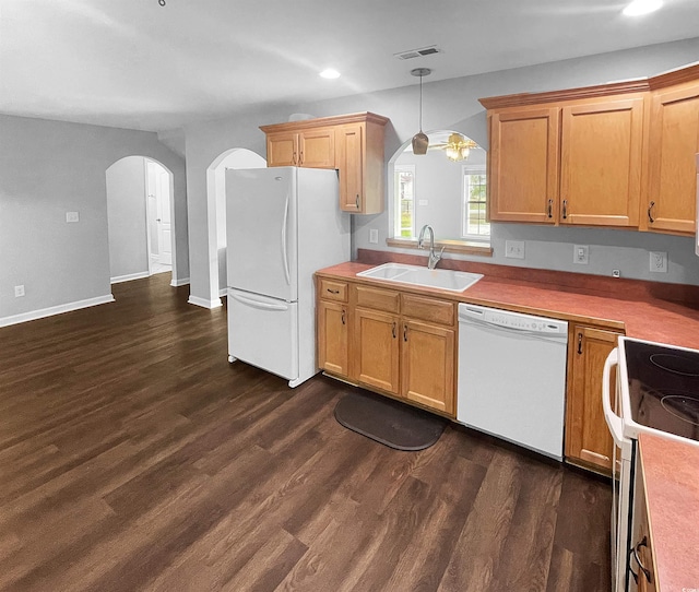 kitchen featuring white appliances, dark hardwood / wood-style floors, hanging light fixtures, and sink