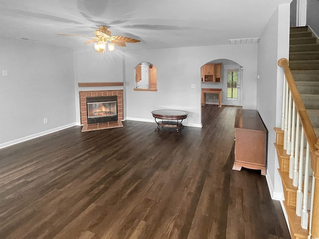 unfurnished living room with a tile fireplace, dark hardwood / wood-style floors, and ceiling fan