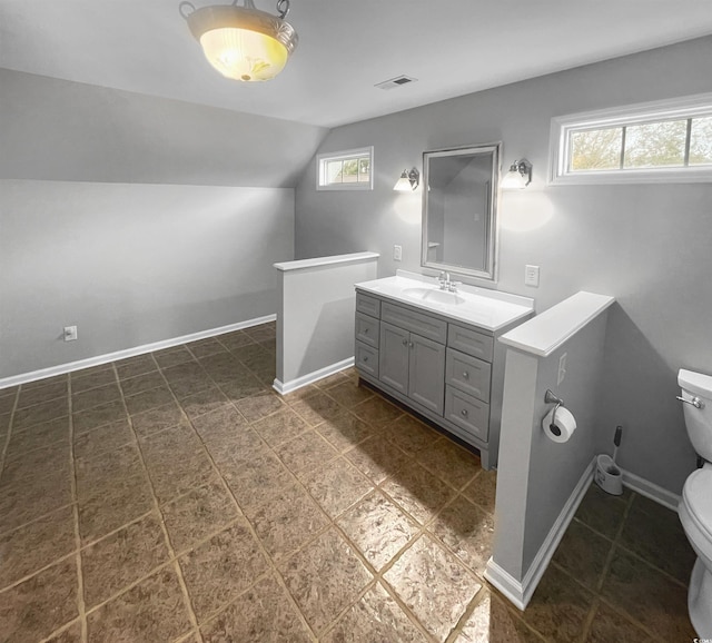 bathroom with vanity, a healthy amount of sunlight, vaulted ceiling, and toilet