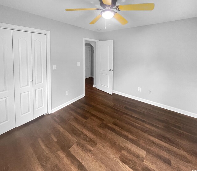 unfurnished bedroom featuring ceiling fan, a closet, and dark hardwood / wood-style floors