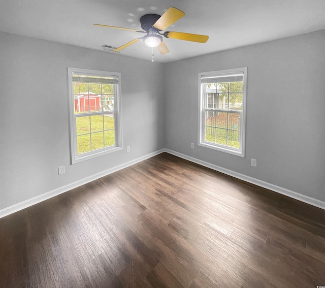 unfurnished room featuring plenty of natural light, ceiling fan, and dark wood-type flooring