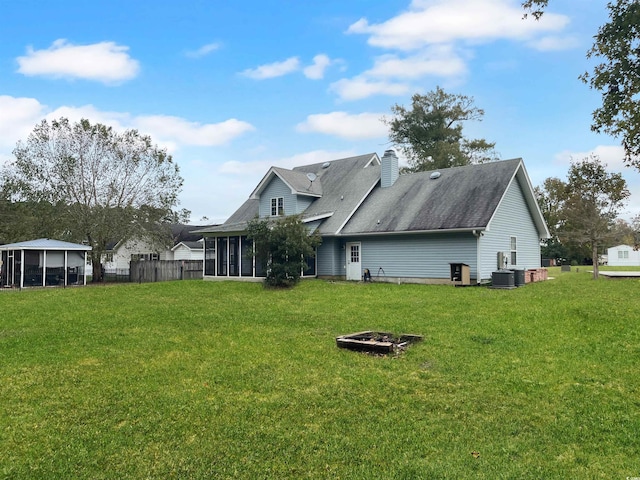 rear view of house featuring a sunroom, a yard, and central air condition unit