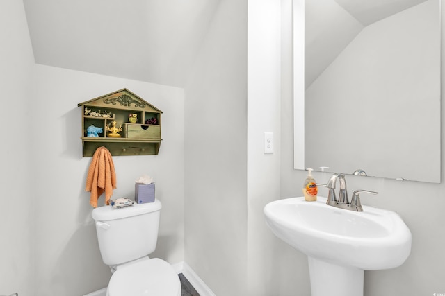 bathroom featuring toilet, lofted ceiling, and sink