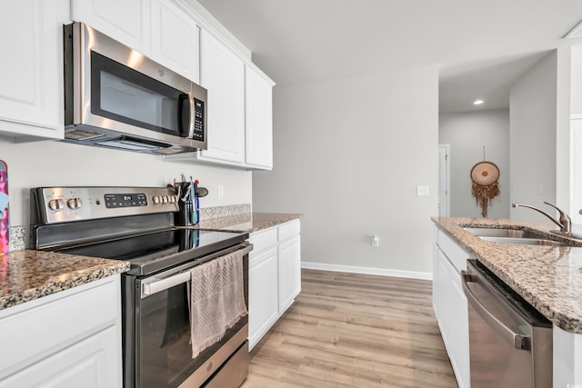 kitchen featuring stone countertops, light hardwood / wood-style floors, sink, and stainless steel appliances