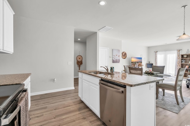 kitchen featuring white cabinetry, hanging light fixtures, stainless steel appliances, light hardwood / wood-style flooring, and a kitchen island with sink