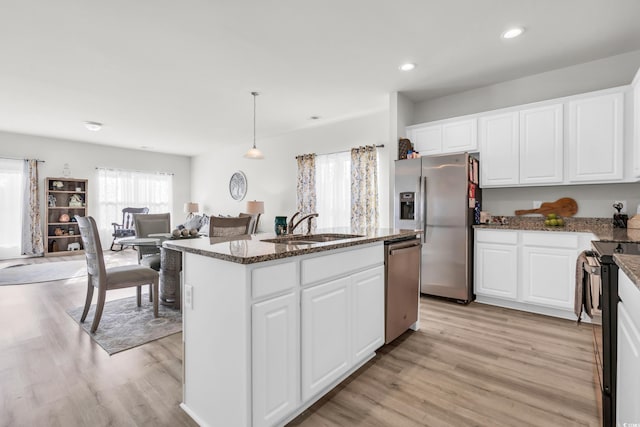 kitchen featuring sink, stainless steel appliances, decorative light fixtures, a center island with sink, and white cabinets