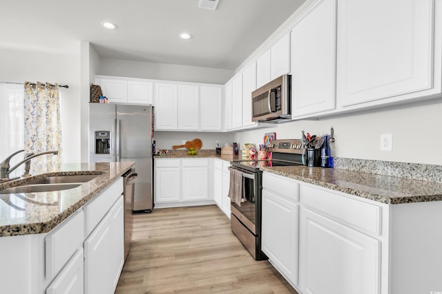 kitchen with sink, white cabinets, stainless steel appliances, and light wood-type flooring