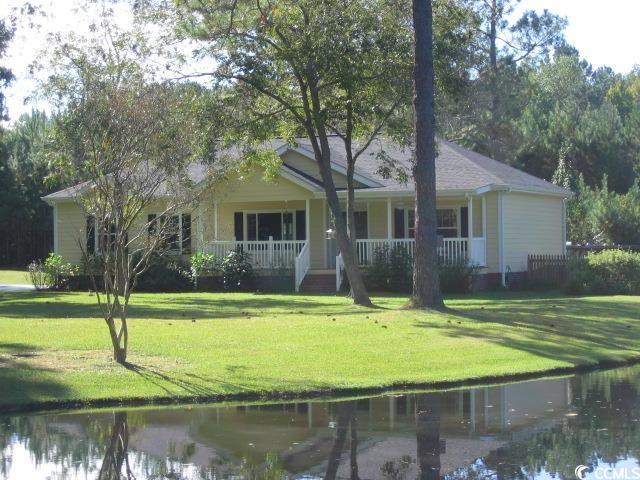 view of front of house featuring a water view, covered porch, and a front lawn