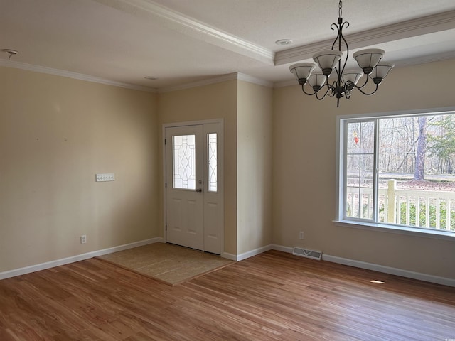 foyer with ornamental molding, light hardwood / wood-style flooring, and a notable chandelier